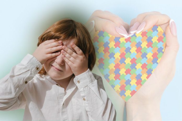 menino tampando os olhos para representar o TEA - Transtorno do Espectro Autista. Ao fundo, compondo a imagem, um mão segurando um coração de quebra cabeça