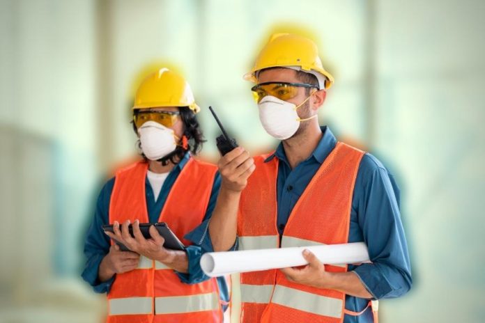 trabalhadores usando EPI como capacetes, coletes e mascaras para evitar doenças ocupacionais