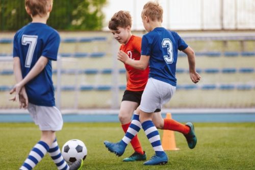 crianças jogando futebol atividades físicas na infância
