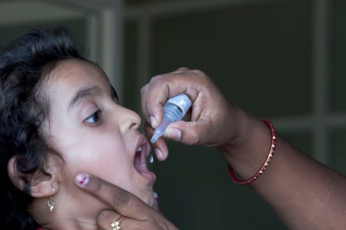 menina toma vacina de gotinha para poliomielite