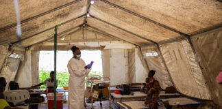 imagem de um dos CTCs do MSF em Cité Soleil, no Haiti. Profissional de saúde em pé, ao centro, leitos estão ocupados com pacientes de cólera.